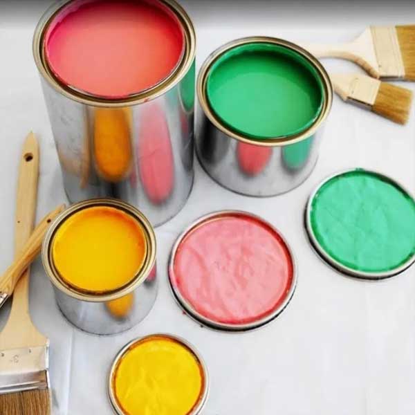 Barattoli di pittura aperti nei toni del rosso, verde e giallo con pennelli accanto