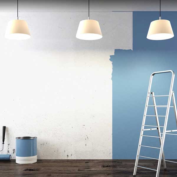 Parete tinteggiata a metà in azzurro, con scala, rullo e barattolo di pittura
