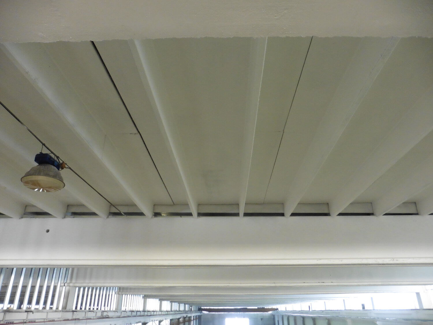 Travi e soffitto di un capannone industriale tinteggiati di bianco