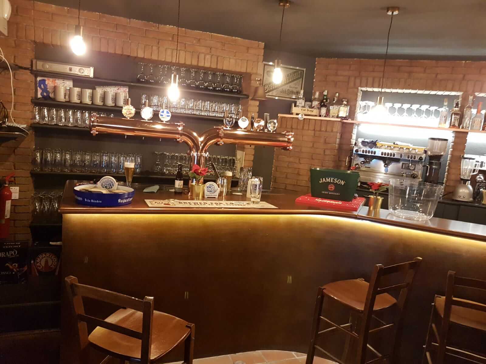 Bancone di una birreria con spine in rame, pareti in mattoni e finitura decorativa dorata sul fronte del bancone