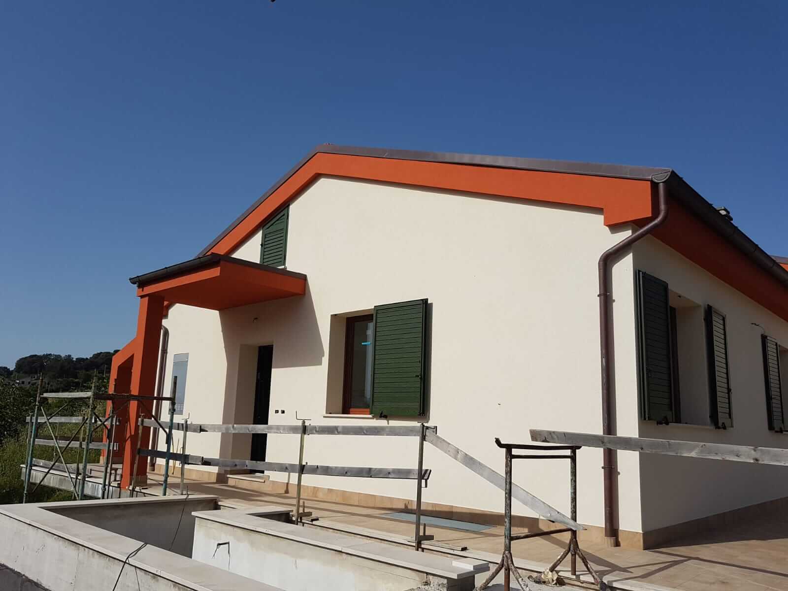 Villa con facciata color crema e cornici del tetto tinteggiate in arancione